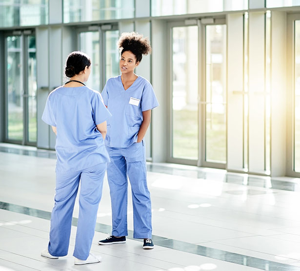 Deux femmes de la fonction publique hospitalière discutent dans un couloir de l'hôpital - MACSF