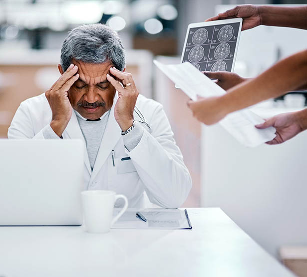 Un médecin surbooké assis à son bureau - MACSF