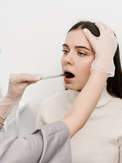 Une femme médecin examine la bouche d'une patiente - MACSF