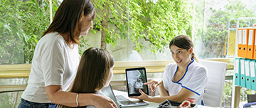 Une mère et sa fille mineure regardent la tablette présentée par la dentiste - MACSF