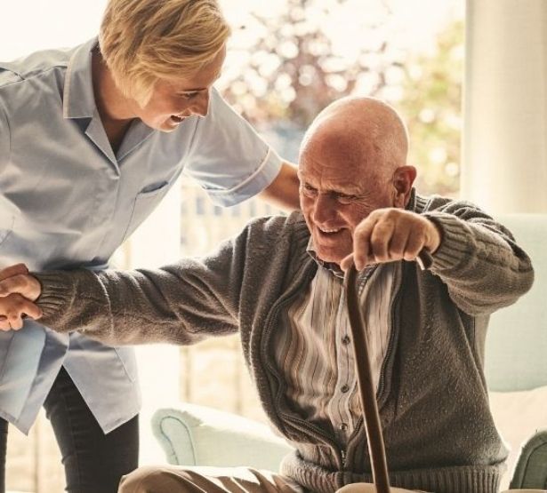 Une aide soignante aide un vieux monsieur.