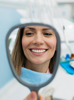 Une jeune femme souriante devant le miroir chez le dentiste - MACSF