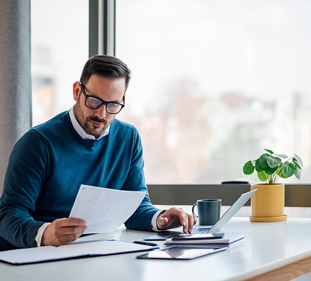 Un homme assis à son bureau lit un document - MACSF