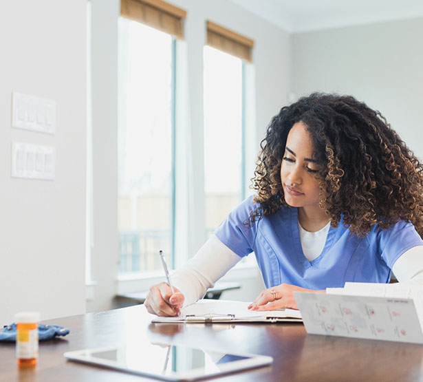 Une infirmière à domicile écrit dans le dossier - MACSF