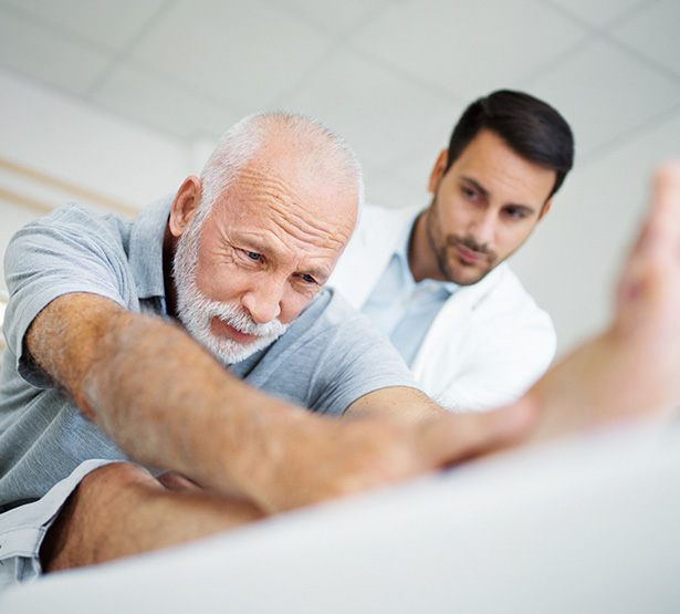 Un kinésithérapeute observe son patient qui s'étire - MACSF