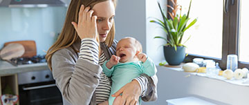 Nourrisson pleure dans les bras de sa maman inquiète - MACSF