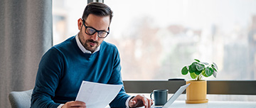 Un homme assis à son bureau lit un document - MACSF