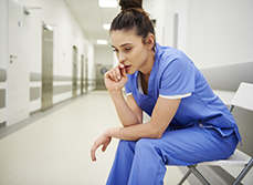 Une soignante assise inquiète assise dans le couloir de l'hôpital - MACSF