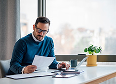 Un homme assis à son bureau lit un document - MACSF