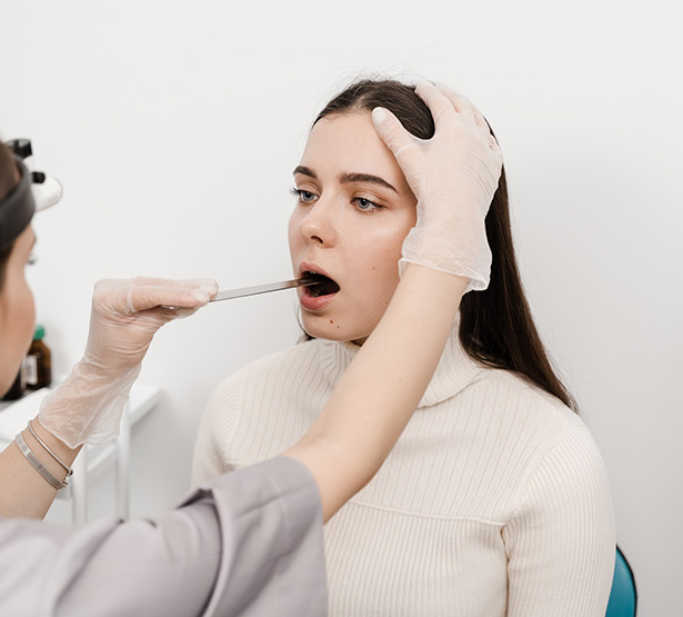 Une femme médecin examine la bouche d'une patiente - MACSF