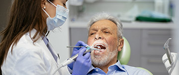 Une femme chirurgien-dentiste soigne un patient - MACSF