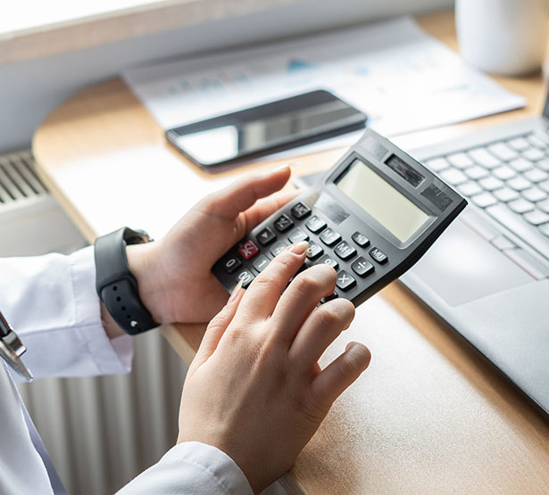 Un médecin tape sur une calculatrice devant son ordinateur - MACSF