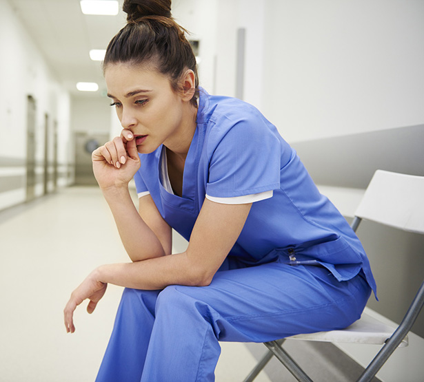 Une soignante assise inquiète assise dans le couloir de l'hôpital - MACSF