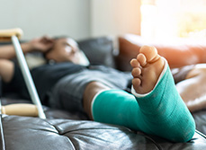 Un homme avec un plâtre à la jambe installé sur son canapé - MACSF