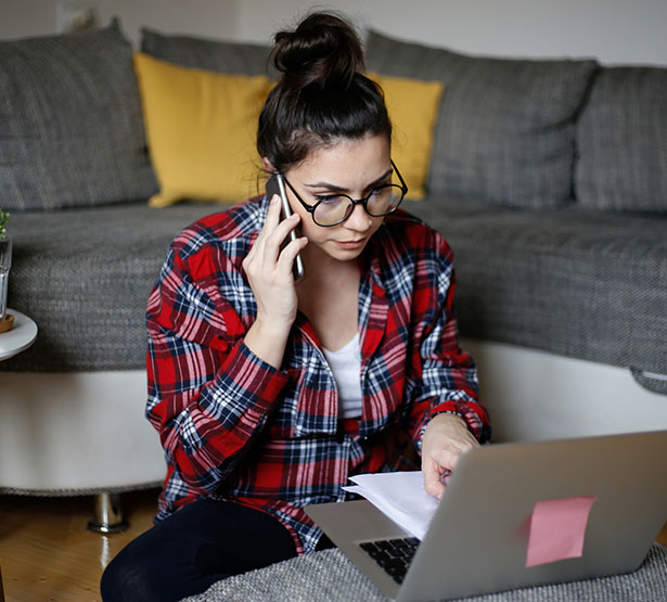 Une jeune femme dans son salon au téléphone devant son ordinateur - MACSF