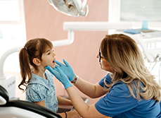 La dentiste examine les dents d'une fillette - MACSF