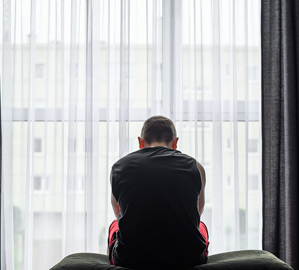 Un homme déprimé assis sur le bord de son lit devant la fenêtre - MACSF