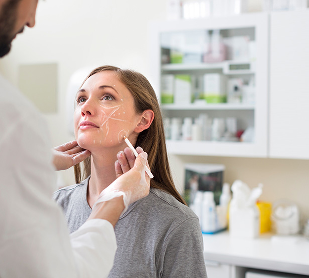 Un chirurgien fait des marques sur le visage d'une patiente en vue d'une chirurgie esthétique - MACSF